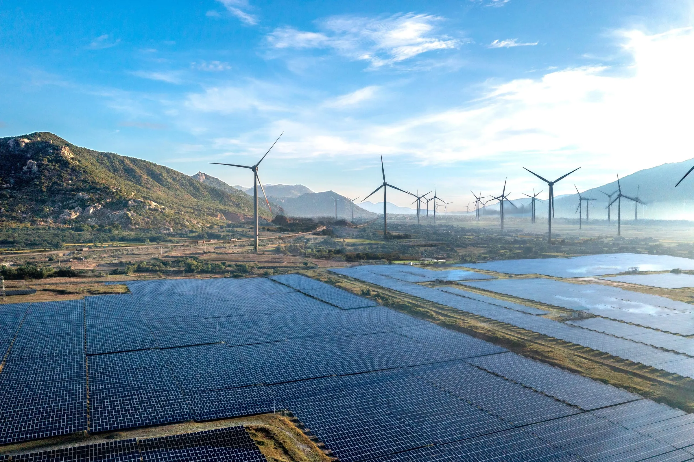 Wind turbines on hills above a valley of solar panels